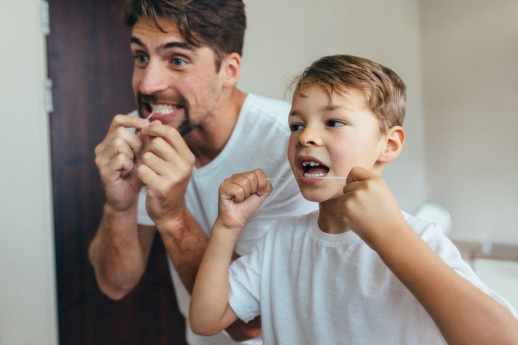 father and son showing how to maintain oral health by brushing teeth